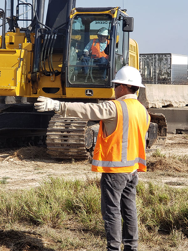 Worker giving instructions to an excavator shovel
